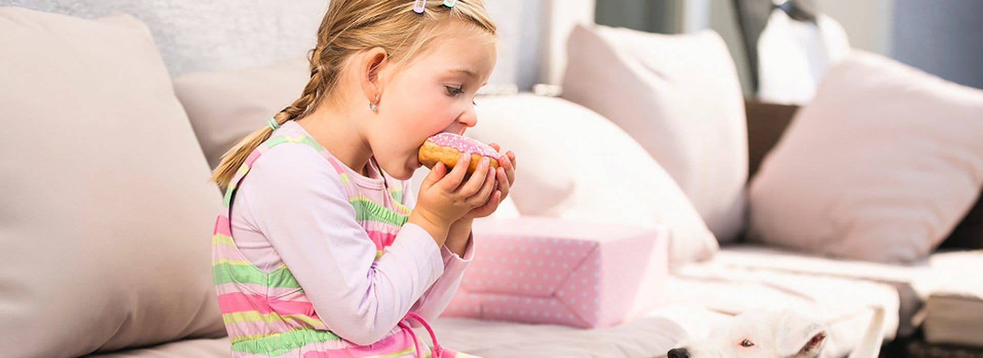 Kind auf Sofa beim Essen eines Donuts