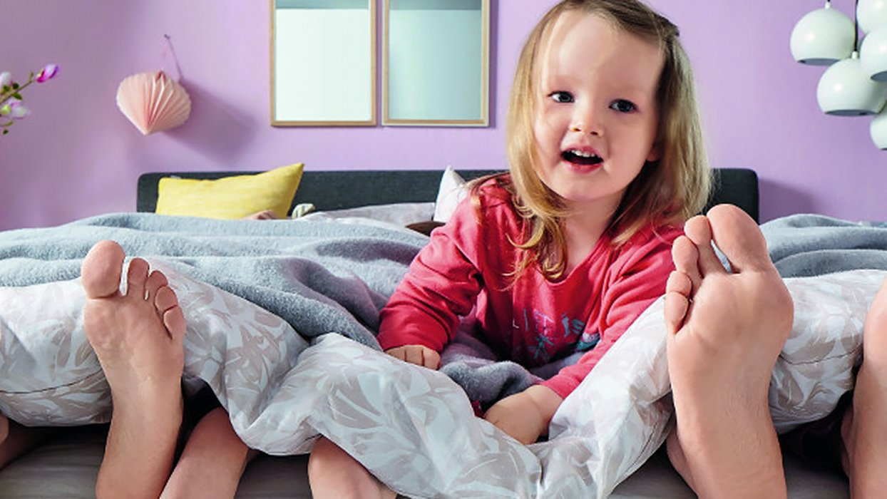 Kind mit Eltern im Boxspringbett