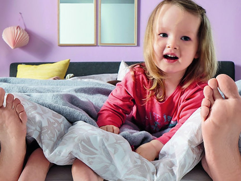 Kind mit Eltern im Boxspringbett