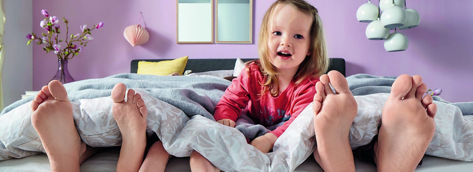 Kind mit Eltern im Boxspringbett
