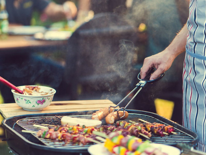 Person wendet das Gemüse und Fleisch auf dem Grill von Berkemeier