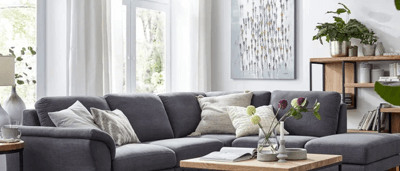 Gemütliches Wohnzimmer, graues Sofa weißer Teppich, helle Vorhänge im Wohnzimmer,
