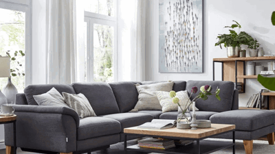 Gemütliches Wohnzimmer, graues Sofa weißer Teppich, helle Vorhänge im Wohnzimmer,