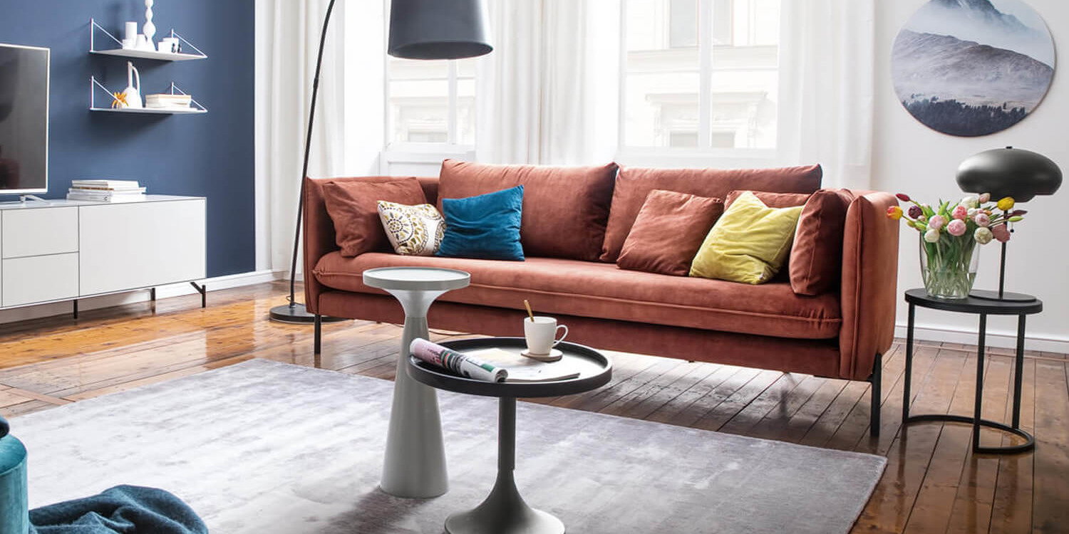 Ausmisten, Aufräumen, Konmari, Death-Cleaning, blaue Wand, Rostbraunes Samtsofa, grauer Teppich