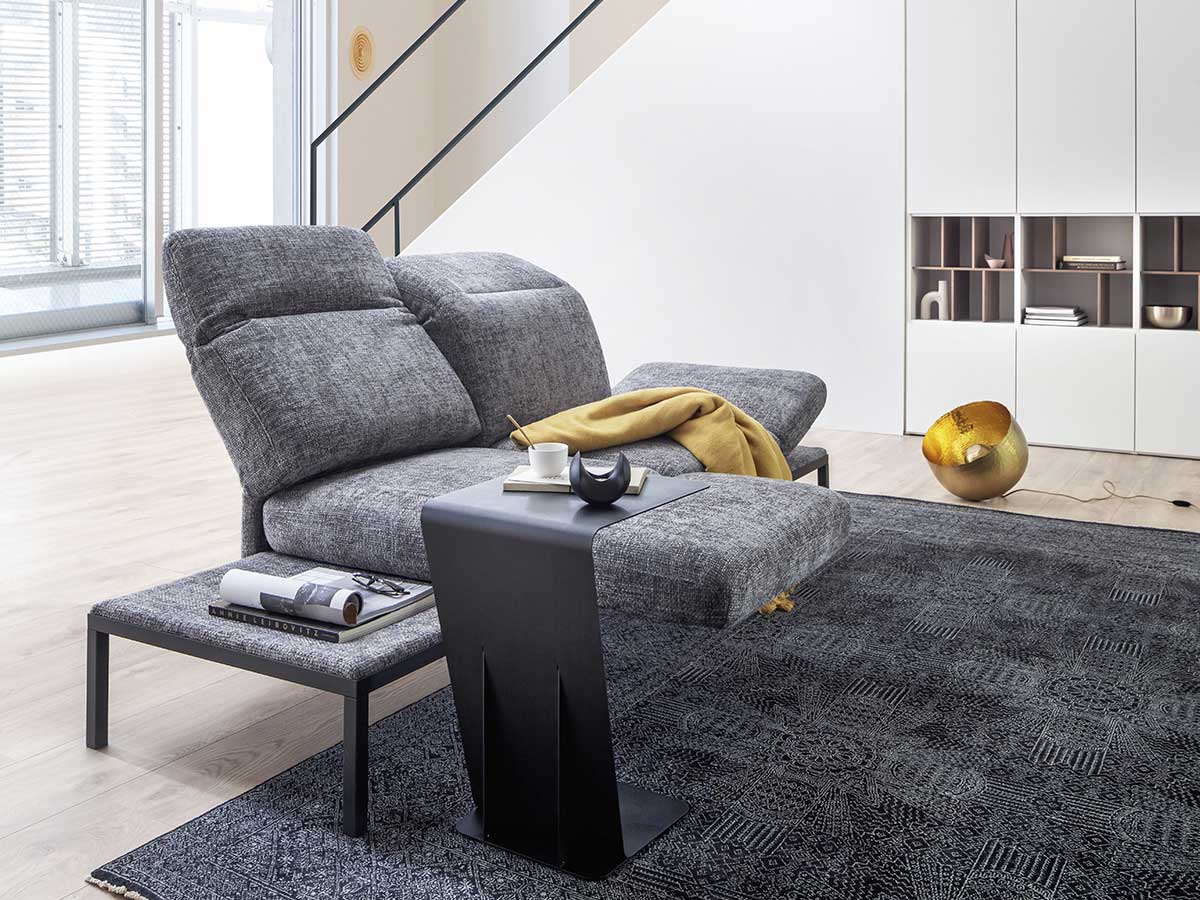 2-Sitzer Sofa aus grauem Stoff in hellem Wohnzimmer mit grauem Teppich