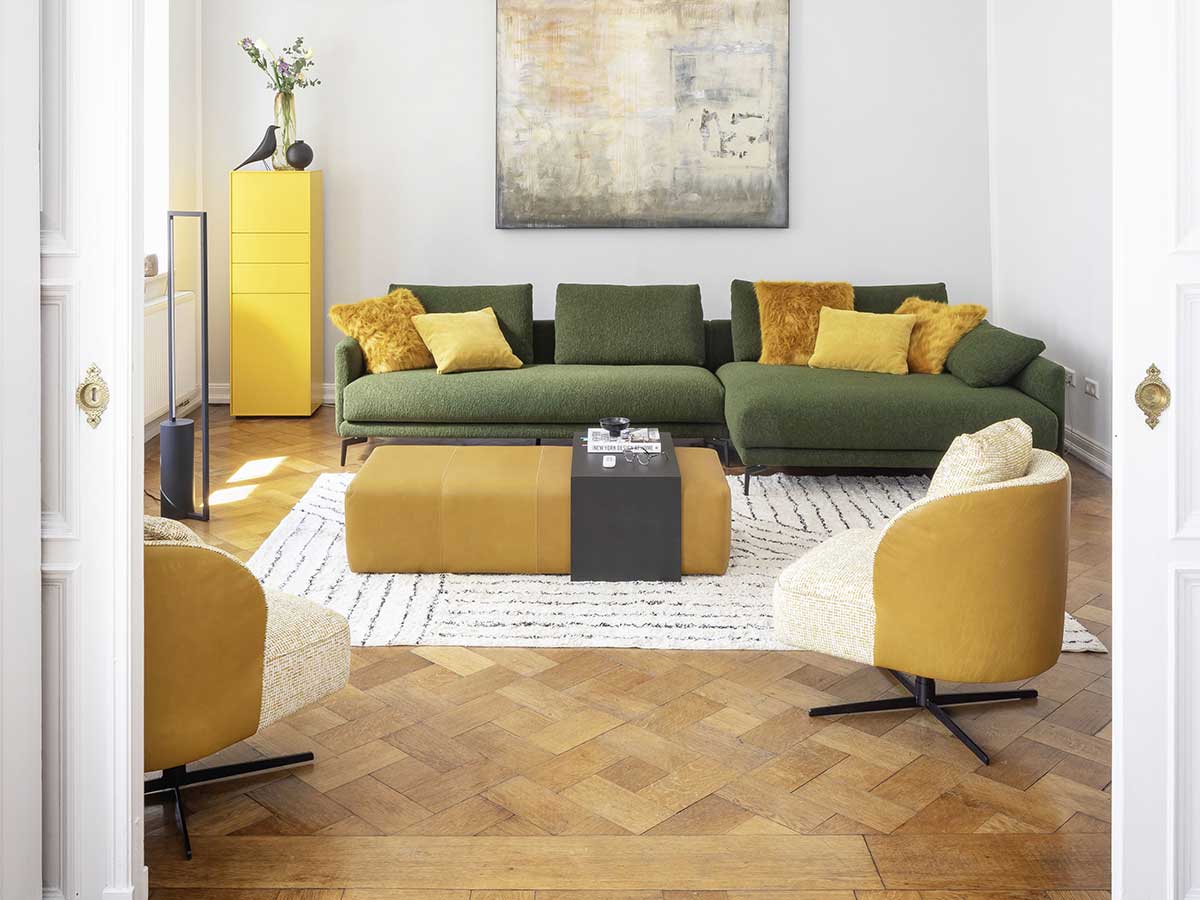 Grüne Couch mit gelbem gepolstertem Tisch und zwei gelben Sesseln