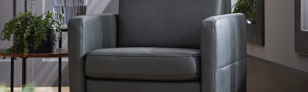 Moderner grauer Ledersessel neben Tisch mit Blumen und Pflanze