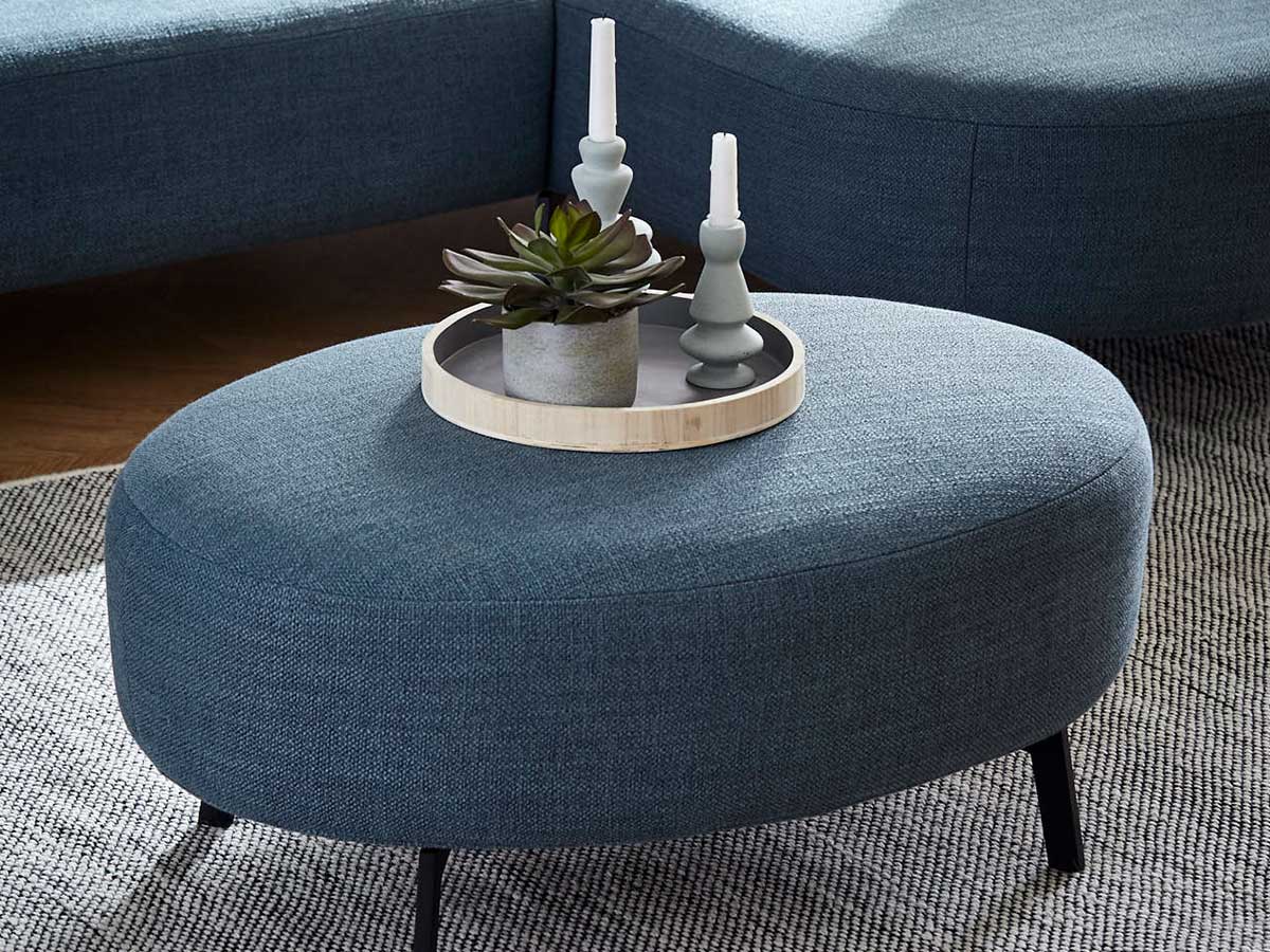 Gepolsterter blauer Couch-Hocker mit Tablett mit Pflanze und zwei Kerzen