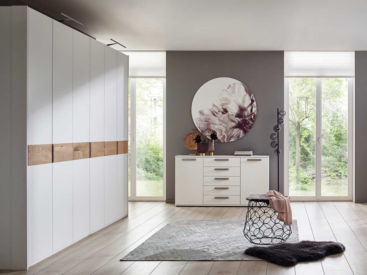 Raum mit großem weißen Schrank, weißer Kommode und grauem Teppich