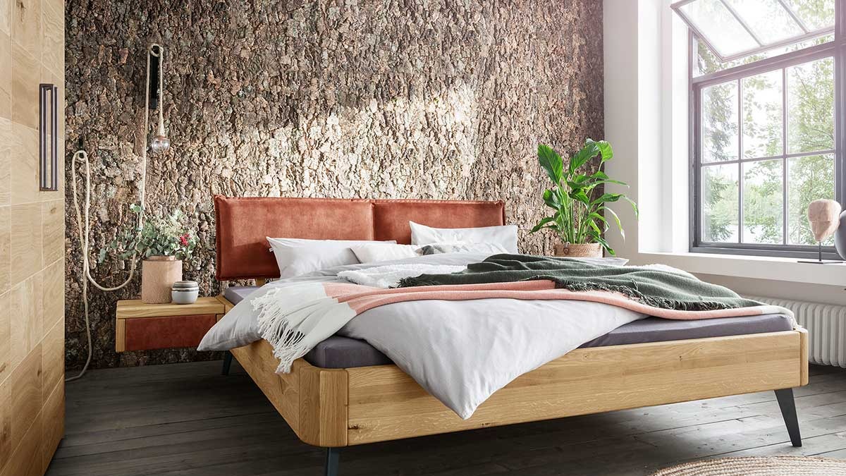 Doppelbett aus Holz vor Natursteinwand