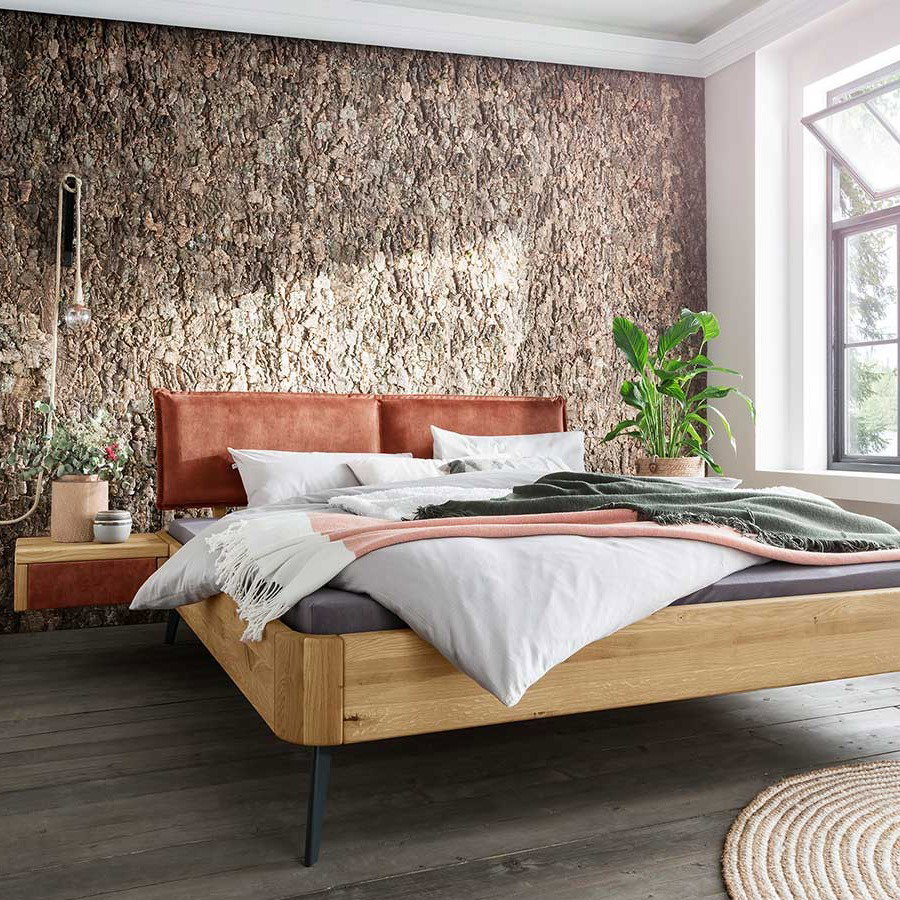 Doppelbett aus Holz vor Natursteinwand