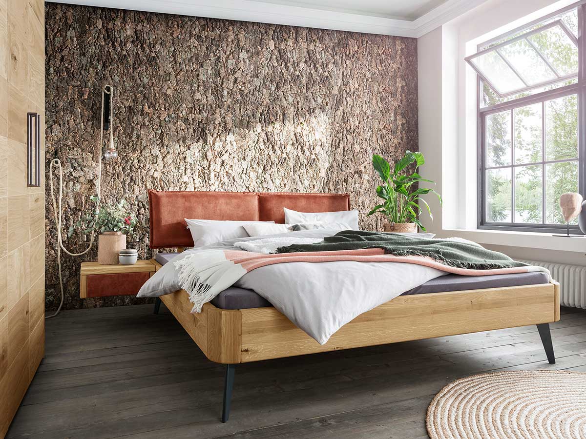 Doppelbett aus Holz vor Natursteinwand