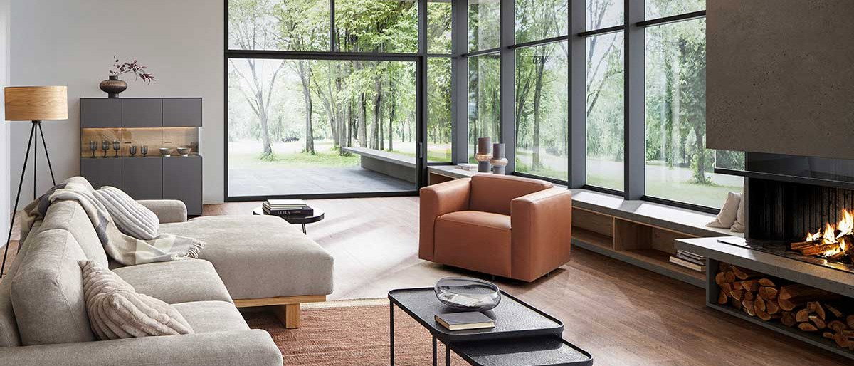 Gemütliches Wohnzimmer, Wohnzimmer mit Kamin, Holzdecke und großen Fenstern
