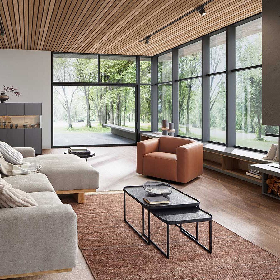 Gemütliches Wohnzimmer, Wohnzimmer mit Kamin, Holzdecke und großen Fenstern