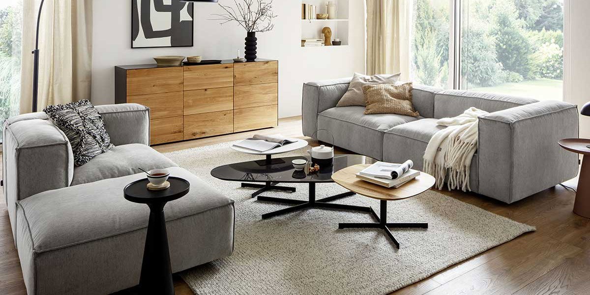 Gemütliches Wohnzimmer im Spätsommer, Wohnzimmer mit hellgrauen Polstermöbeln, naturfarbenem Sideboard und schwarzen Dekoartikeln
