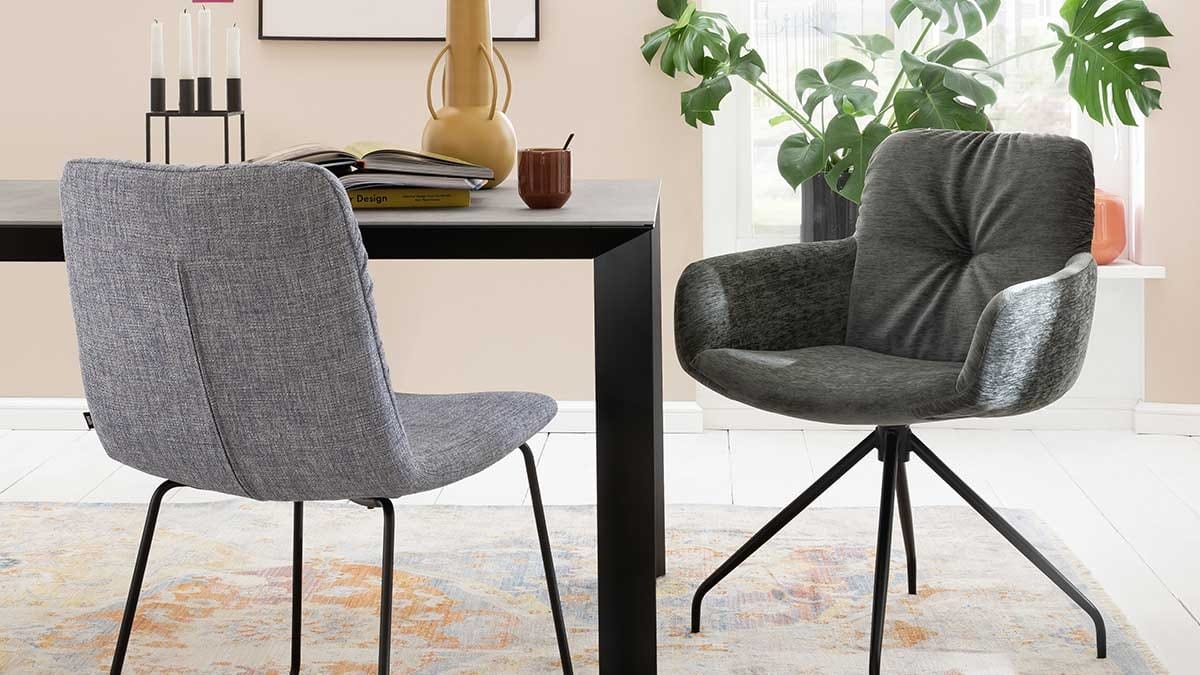 Zwei gepolsterte Esszimmerstühle an einem schwarzen Tisch mit Büchern, Tasse und Vase