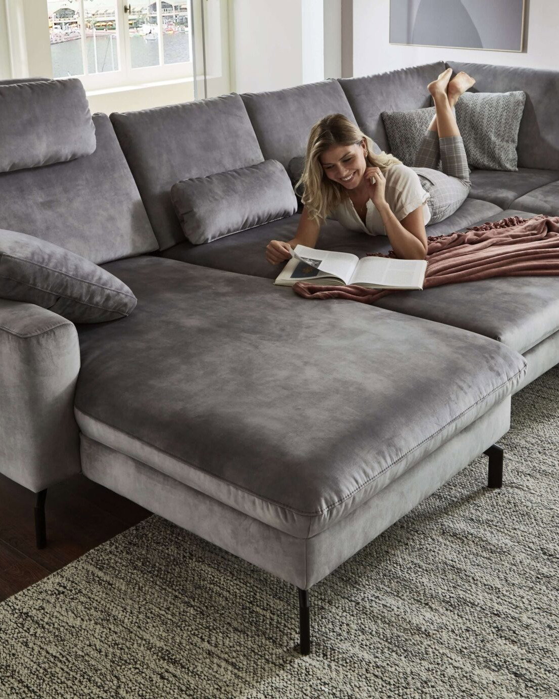 Wohnlandschaft in Silbergrau aus weichem Velour mit Longchair, schwarzem Metallgestell und großzügiger Eckform als gemütlicher Mittelpunkt im Wohnzimmer