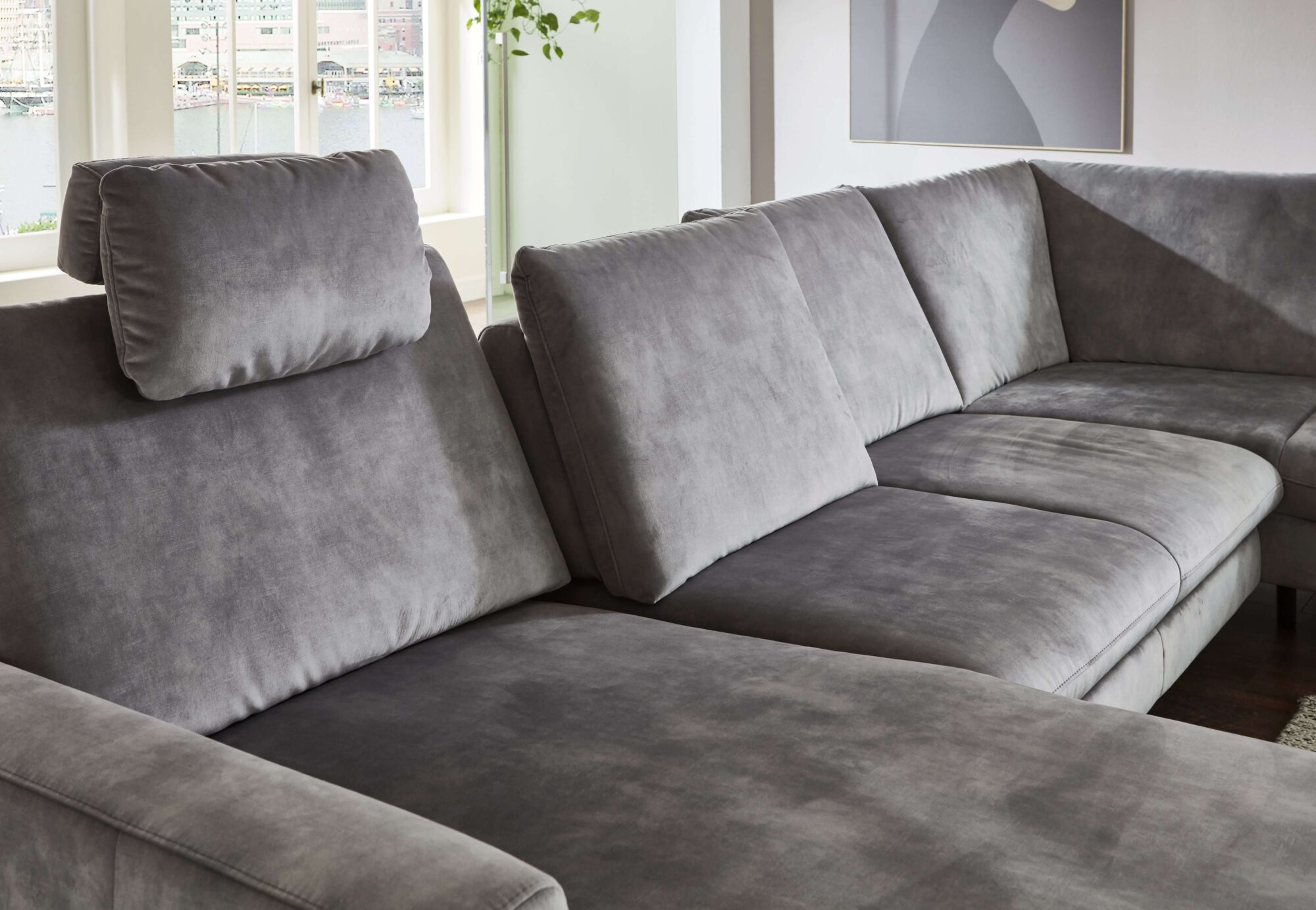 Wohnlandschaft in Silbergrau aus weichem Velour mit Longchair, schwarzem Metallgestell und großzügiger Eckform als gemütlicher Mittelpunkt im Wohnzimmer