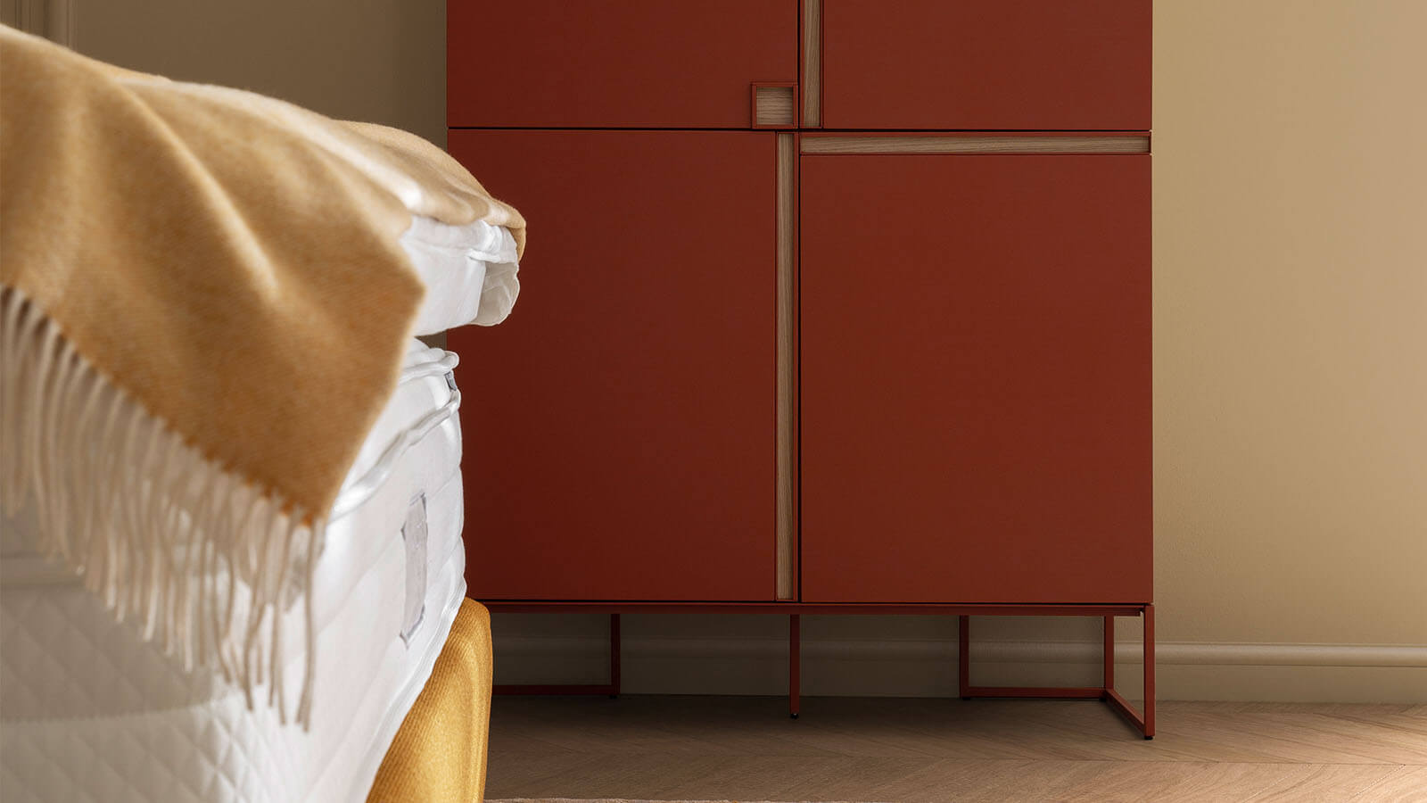 Boxspringbett Navelli von Contur mit hohem, gepolstertem Kopfteil, edlem Stoffbezug in Grau oder Kurkuma und großzügiger Liegefläche als stilvoller Mittelpunkt eines modernen Schlafzimmers.