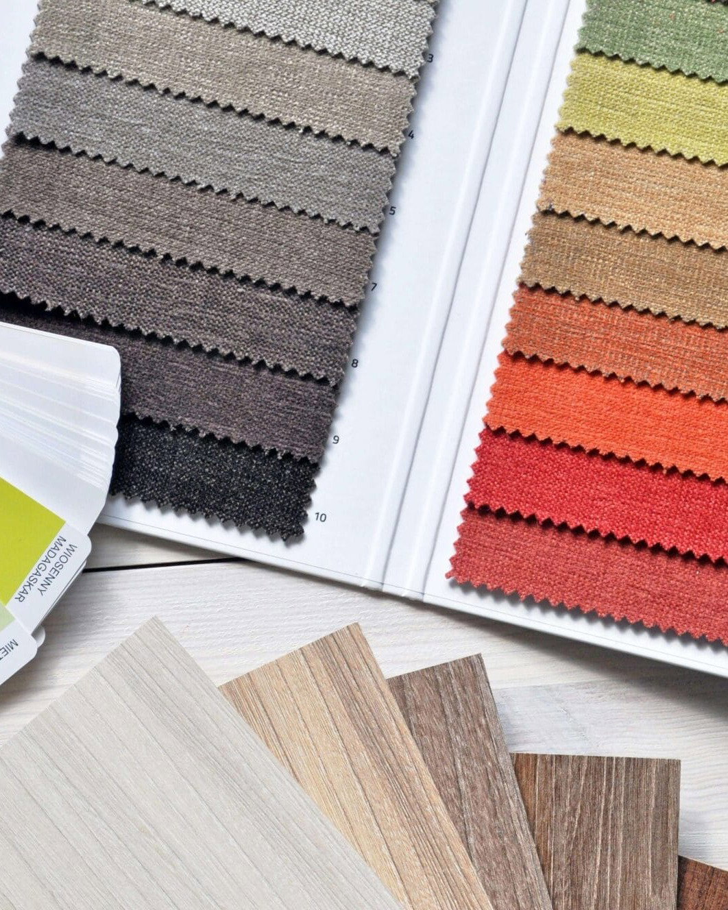 Farb- und Stoffmuster, Holzproben und Farbfächer auf einem Tisch zur Auswahl von Einrichtungsmaterialien