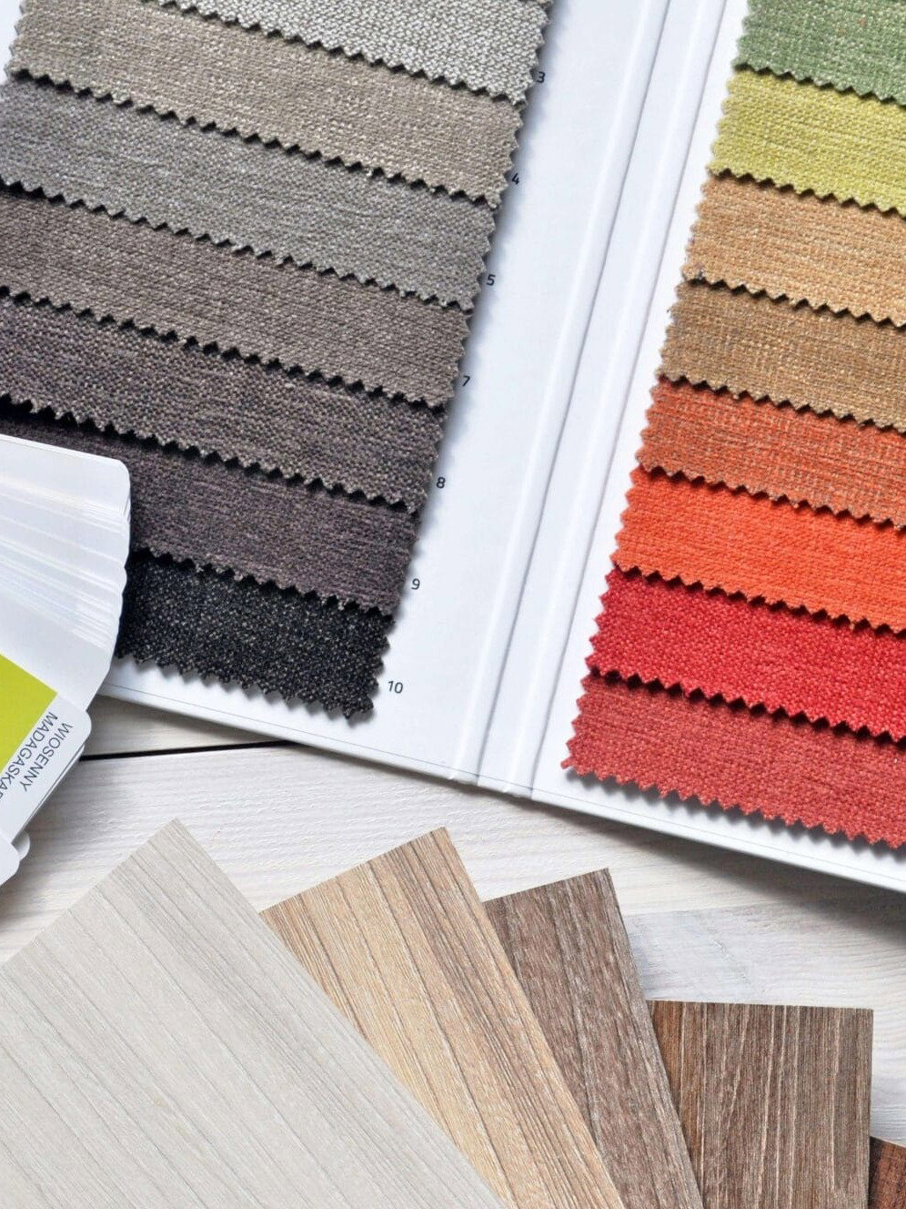 Farb- und Stoffmuster, Holzproben und Farbfächer auf einem Tisch zur Auswahl von Einrichtungsmaterialien
