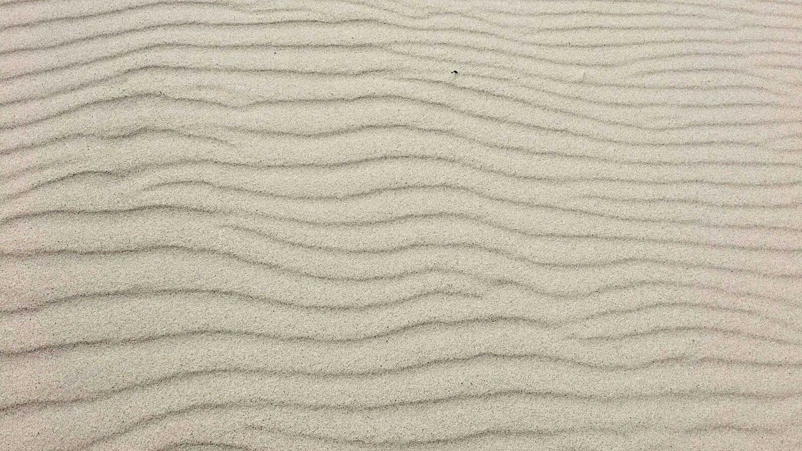 Feine Sandoberfläche mit wellenförmigen Strukturen – Inspiration für helle Naturfarben und minimalistisches Interior Design.