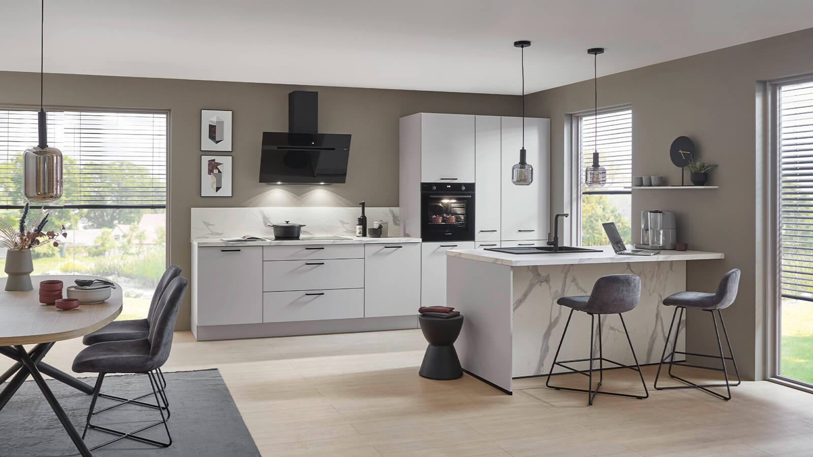 Offene, moderne Küche mit Essbereich, seidengrauen Fronten und heller Arbeitsplatte in Marmoroptik, gestaltet im klaren EM-Laser-Design.