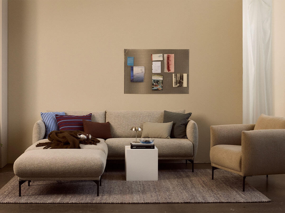 Ecksofa Joana von Jakobsen Copenhagen in Beige mit Chenilleflachgewebe, schwarzem Metallgestell, großzügiger Sitzfläche und losen Rückenkissen im modernen skandinavischen Design.