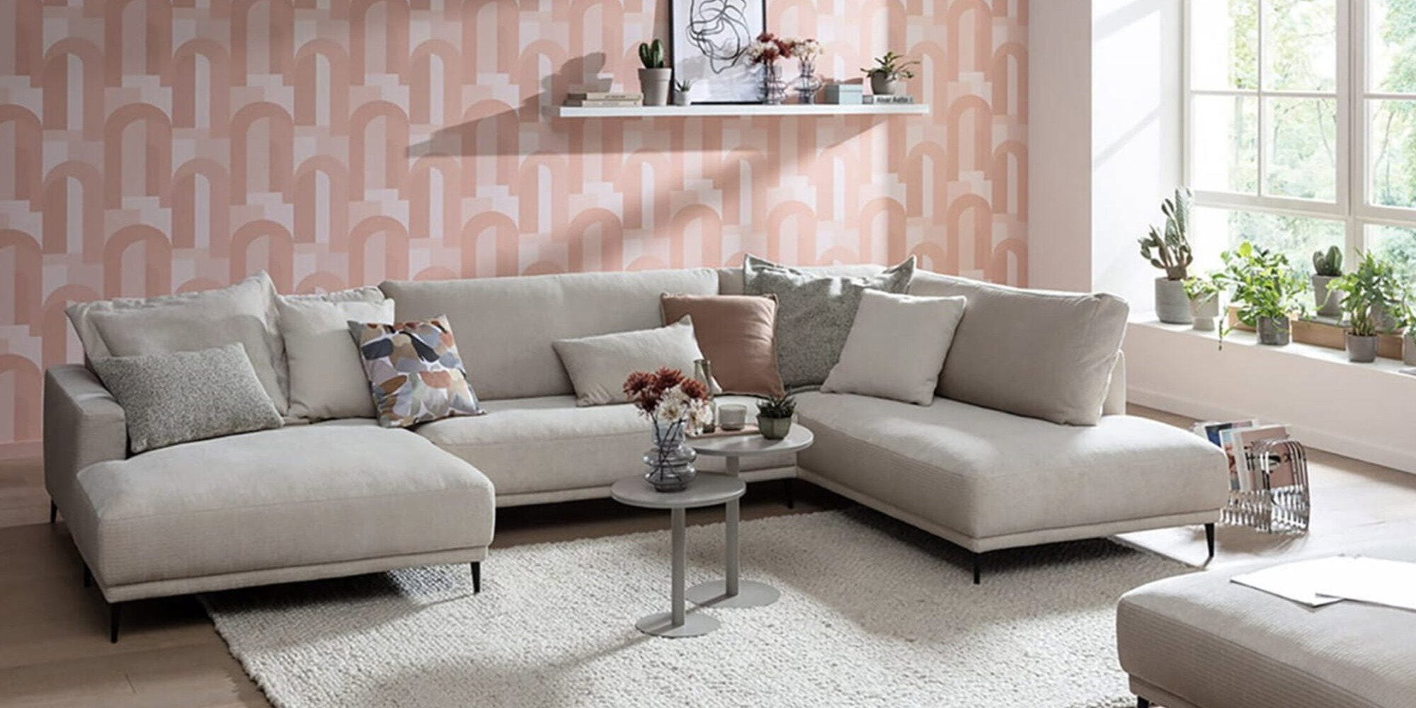 Helles Ecksofa im modernen Wohnzimmer mit Teppich, Couchtisch und großer Fensterfront als Beispiel für die richtige Möbelpositionierung im Wohnraum.