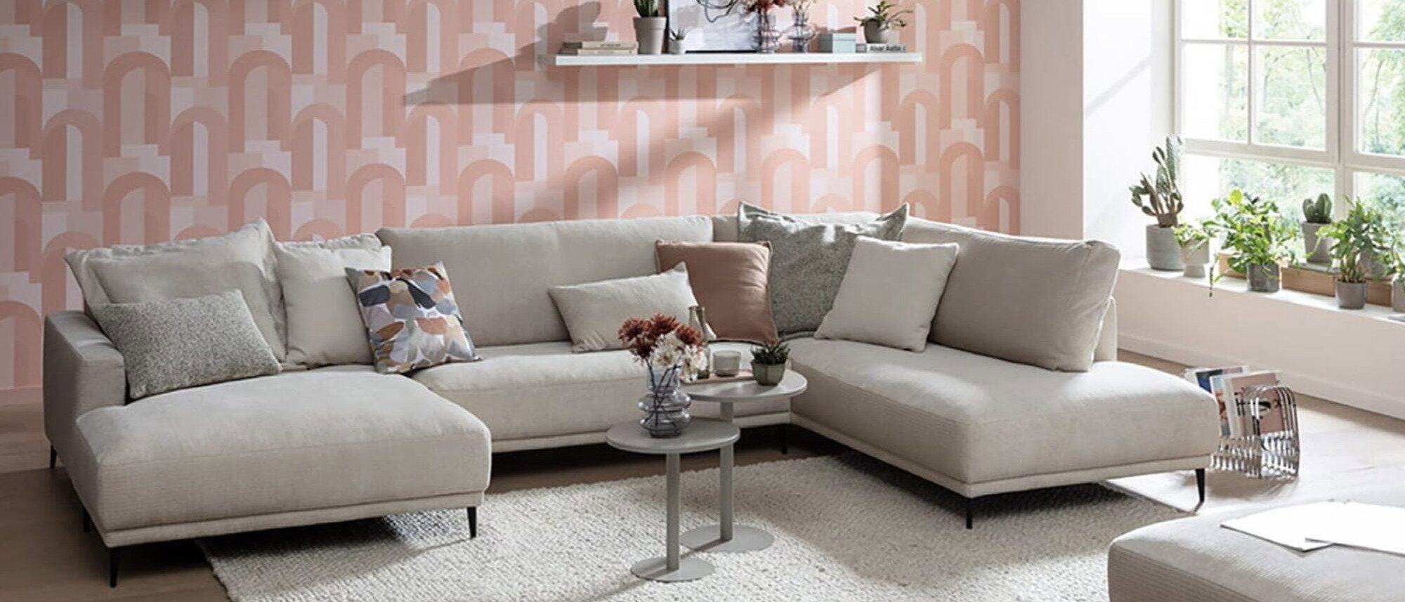 Helles Ecksofa im modernen Wohnzimmer mit Teppich, Couchtisch und großer Fensterfront als Beispiel für die richtige Möbelpositionierung im Wohnraum.