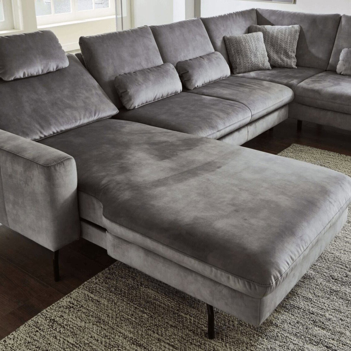 Großes graues Ecksofa mit verstellbaren Kopfstützen in einem modernen Wohnzimmer.