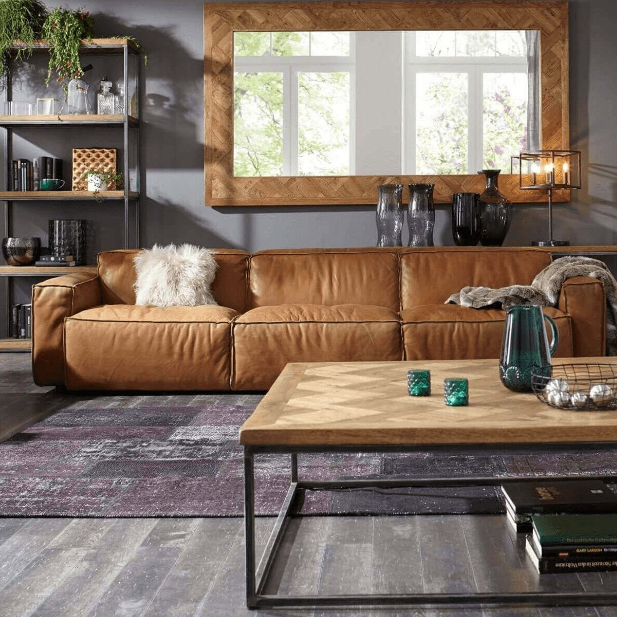 Cognacfarbenes Ledersofa mit Couchtisch und großem Wandspiegel in einem stilvollen Wohnzimmer.