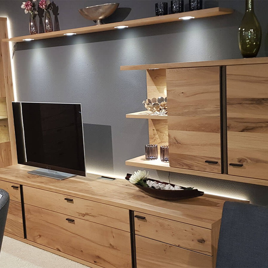 Großzügige Wohnkombination aus heller geölter Eiche mit beleuchteter Vitrine, breitem Lowboard, Hängeschrank und Wandboard.