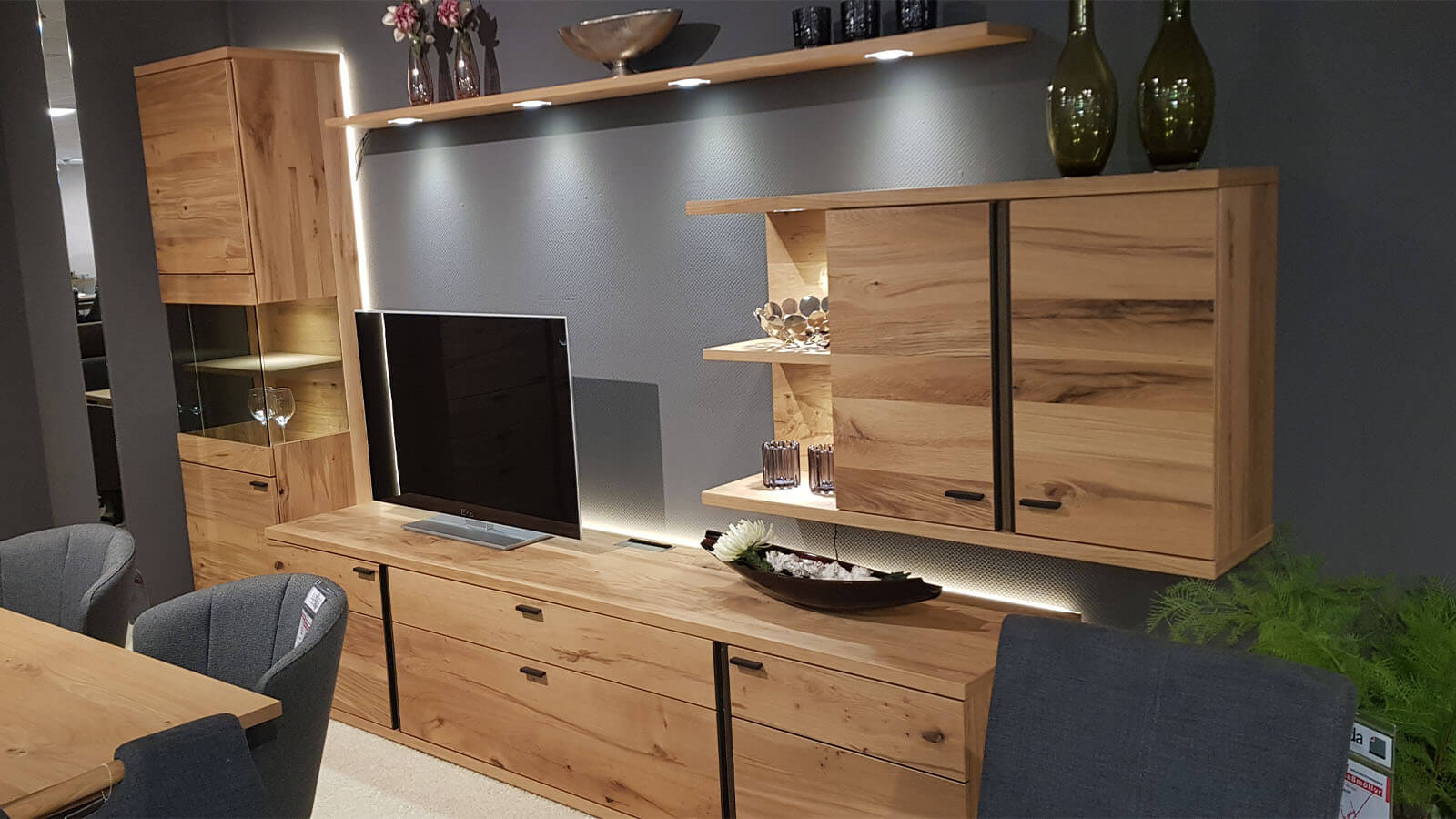 Großzügige Wohnkombination aus heller geölter Eiche mit beleuchteter Vitrine, breitem Lowboard, Hängeschrank und Wandboard.
