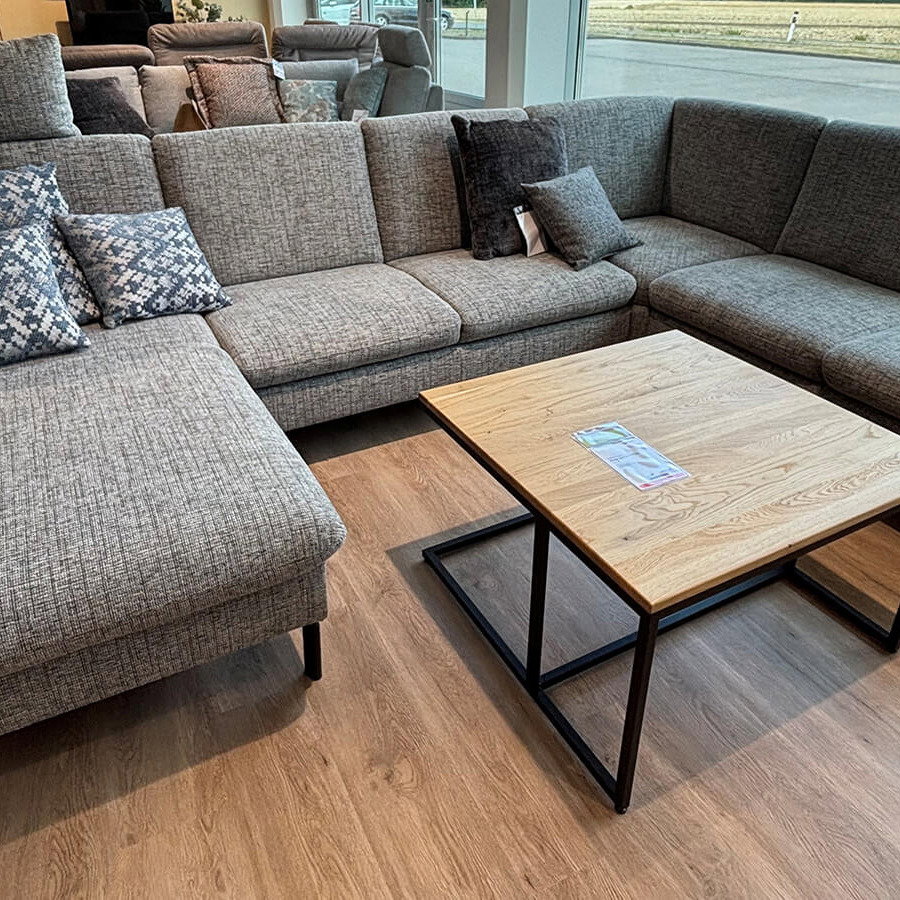 Moderne Wohnlandschaft in Silber mit großzügiger Sitzfläche, schwarzen Füßen und echtem Rücken.