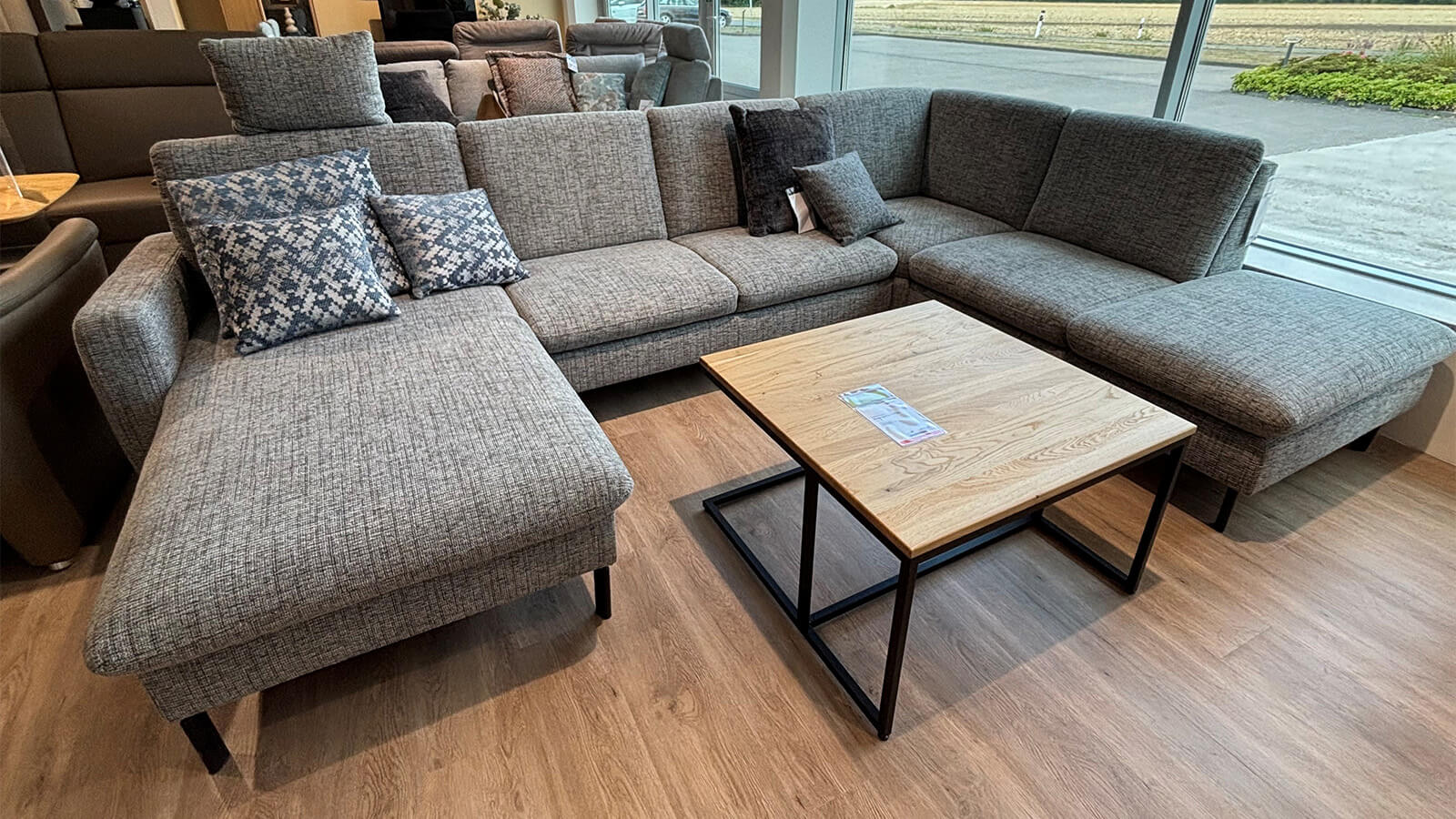 Moderne Wohnlandschaft in Silber mit großzügiger Sitzfläche, schwarzen Füßen und echtem Rücken.