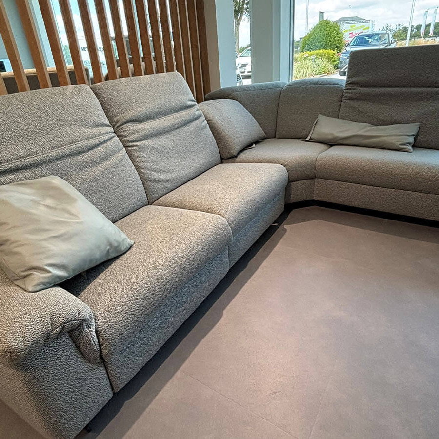 Wohnlandschaft in Q2 Rustic Azuro mit Relaxfunktion, manuell verstellbaren Kopfteilen, Stauraumhocker, Kissen und anthrazitfarbener Metallkufe.