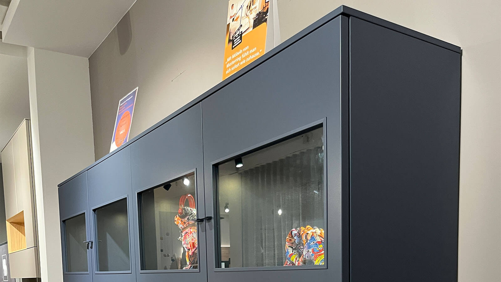 Breites Highboard in Atlantikblau mit hochwertiger Lackoberfläche, vier gleichmäßig angeordneten Frontsegmenten, farbgleichen Griffen und filigranem Kufengestell für eine klare, geradlinige Wohnraumgestaltung.
