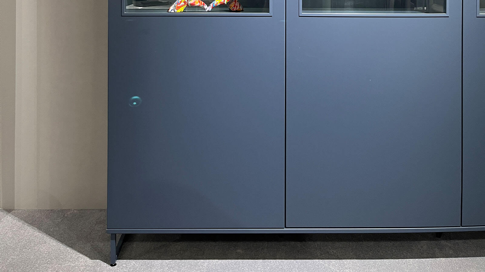 Breites Highboard in Atlantikblau mit hochwertiger Lackoberfläche, vier gleichmäßig angeordneten Frontsegmenten, farbgleichen Griffen und filigranem Kufengestell für eine klare, geradlinige Wohnraumgestaltung.