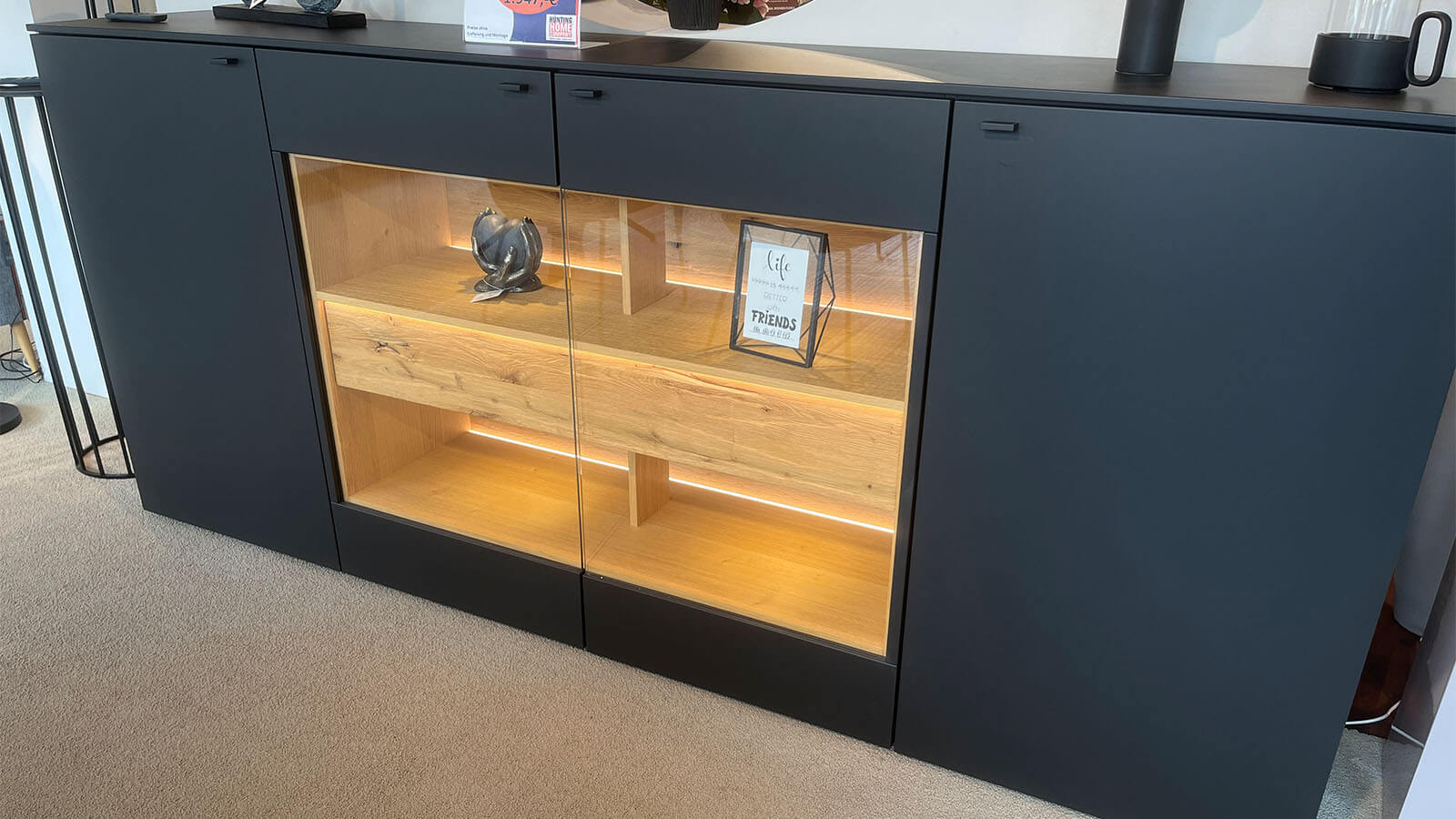 Großes Sideboard in mattem Anthrazit mit grifflosen Fronten, geölten Eiche-Massivholz-Akzenten und integrierter Beleuchtung