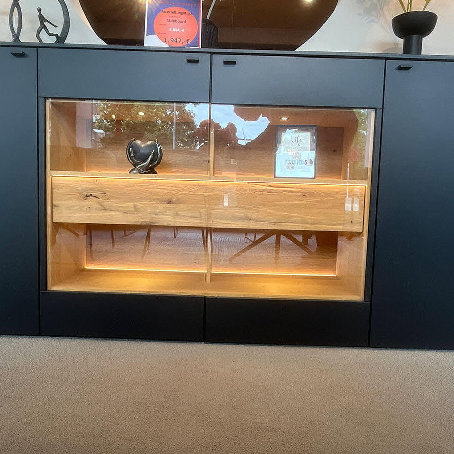 Großes Sideboard in mattem Anthrazit mit grifflosen Fronten, geölten Eiche-Massivholz-Akzenten und integrierter Beleuchtung