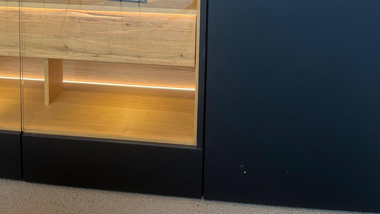 Großes Sideboard in mattem Anthrazit mit grifflosen Fronten, geölten Eiche-Massivholz-Akzenten und integrierter Beleuchtung