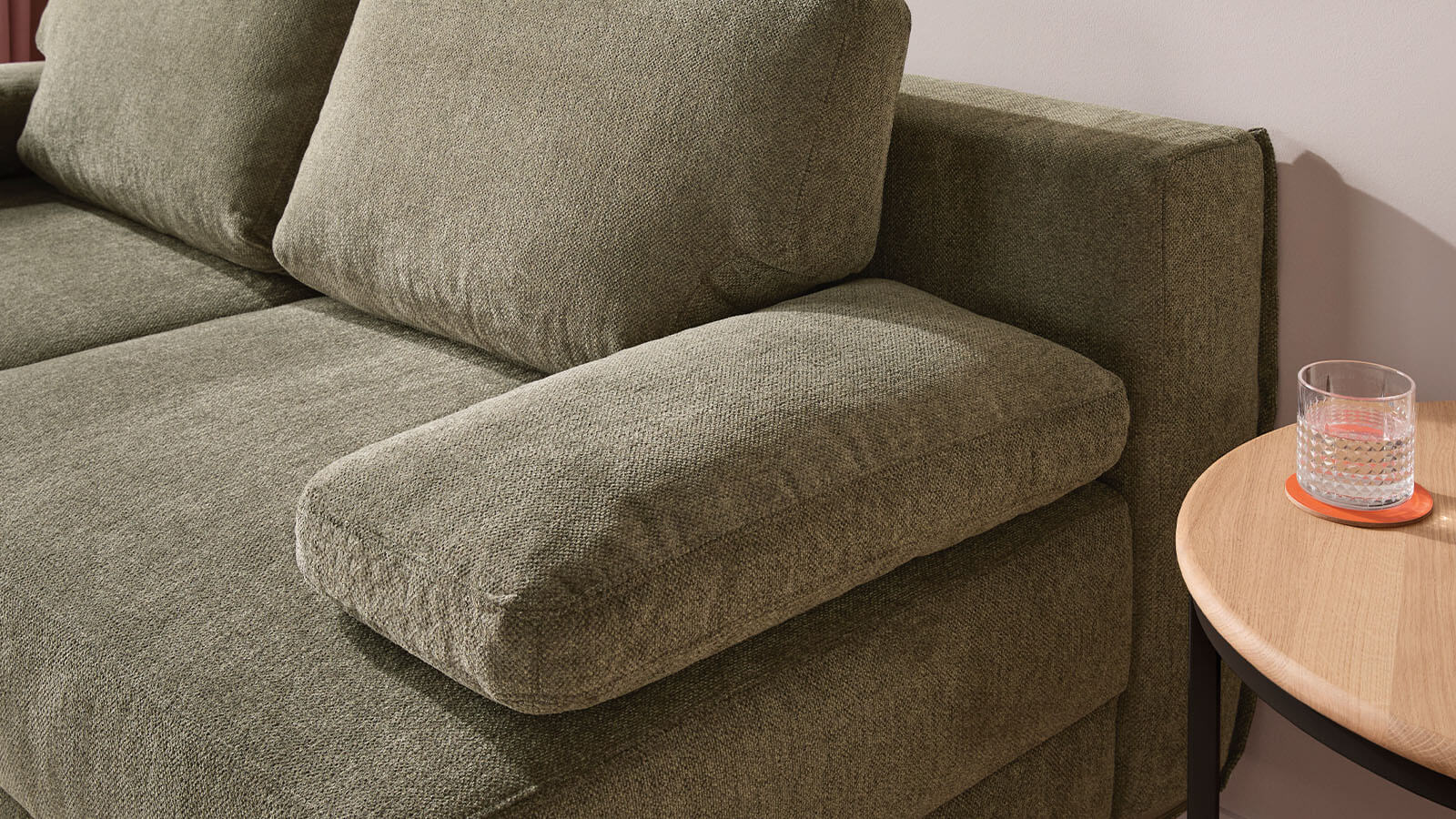 Großzügiges grünes Schlafsofa mit weichem Stoffbezug, lässiger Polsterung und gemütlichen Armlehnenkissen. Die schwarzen Metallfüße setzen einen modernen Akzent, während der integrierte Bettkasten praktischen Stauraum bietet.