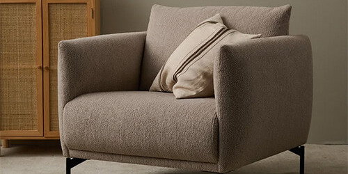Eleganter Stoffsessel in Grau-Beige von Jakobsen Copenhagen mit weicher Polsterung und zeitloser Formensprache als stilvoller Blickfang in einem skandinavisch eingerichteten Wohnzimmer.