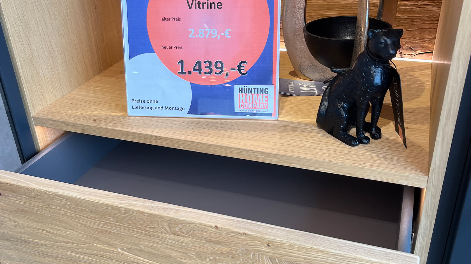 Hohe Vitrine in mattem Anthrazit mit grifflosen Türen, Akzenten aus geölter Massivholz-Eiche und stimmungsvoller Innenbeleuchtung