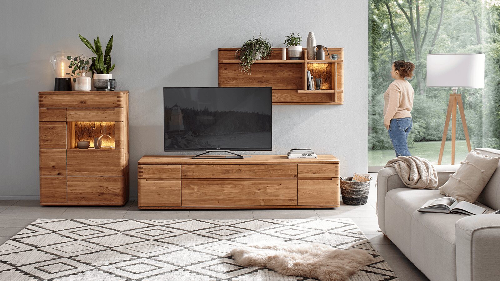 Massive Wohnwand Cartago Soft aus naturgeölter Wildeiche mit integriertem LED-beleuchtetem Wandpaneel und Highboard in wohnlicher Einrichtung