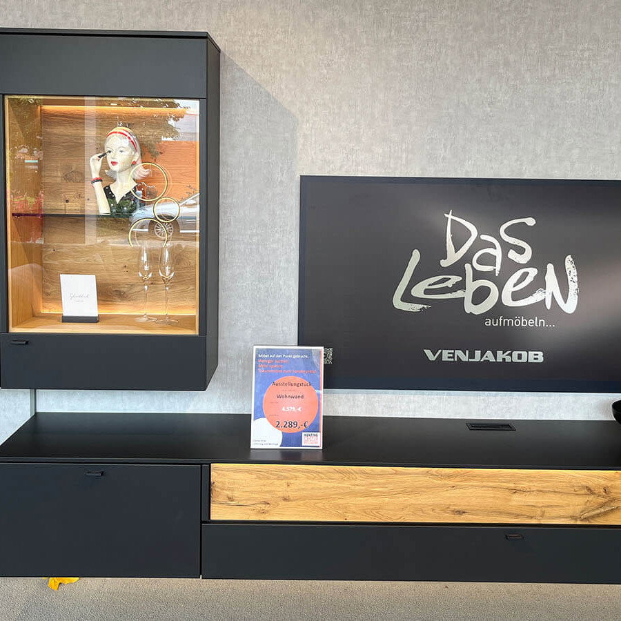 Moderne Wohnwand mit anthrazitfarbenem Mattlack, Akzenten aus geölter Eiche Massivholz, schwebendem Lowboard, Hängevitrine und stimmungsvoller LED-Beleuchtung.