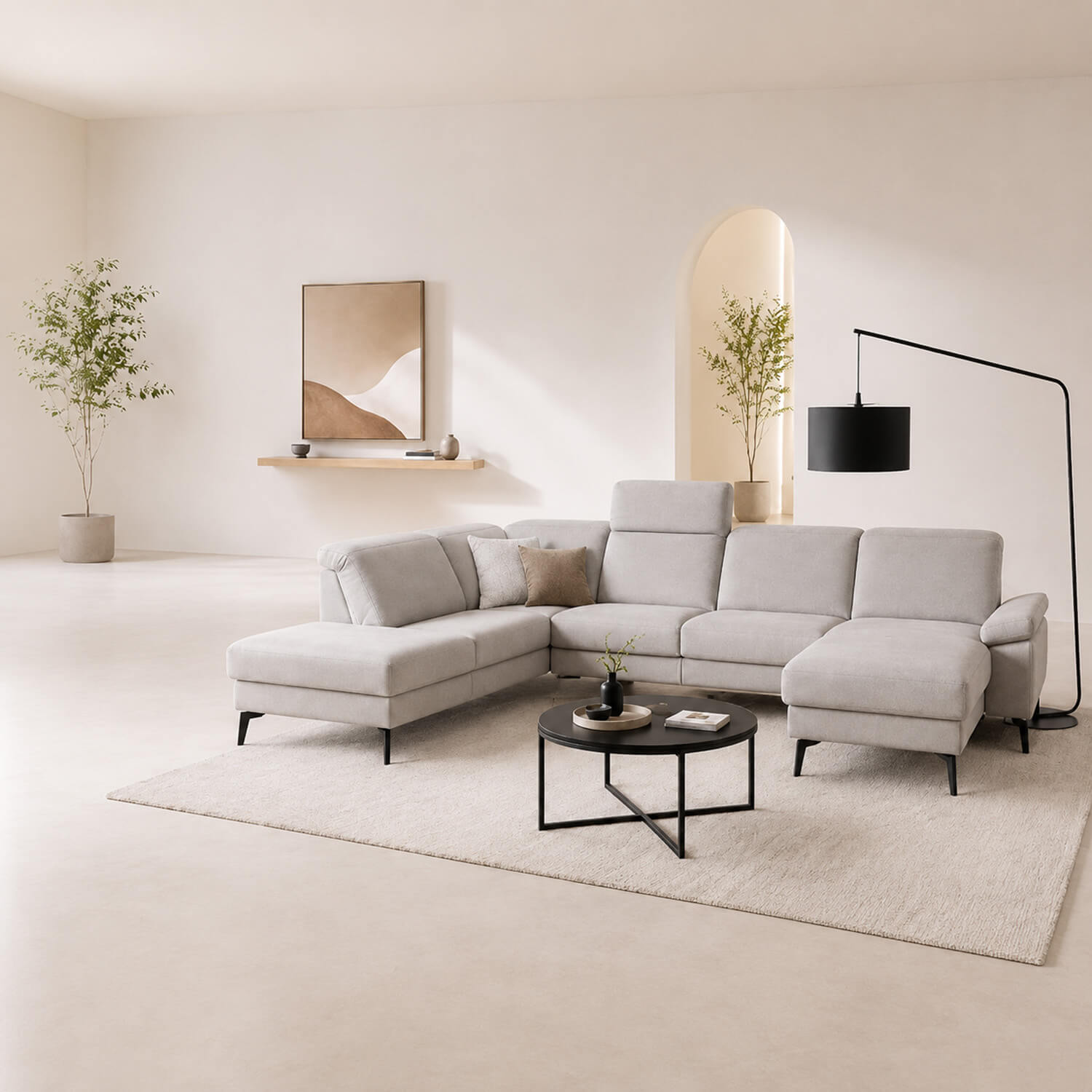 Helles, modernes Wohnzimmer mit großer hellgrauer Wohnlandschaft, schwarzem Couchtisch und minimalistischer Stehleuchte in warmen Beigetönen.