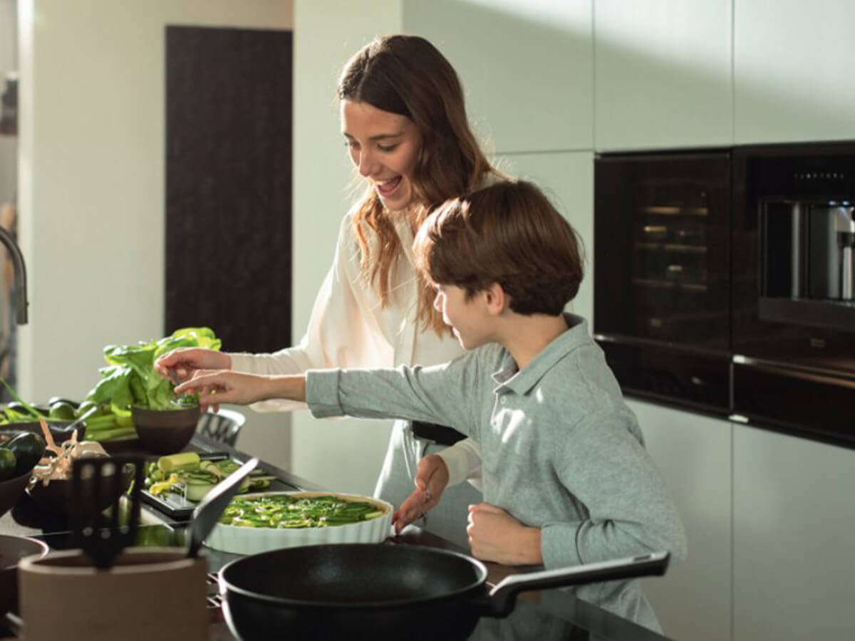 Mutter und Kind bereiten gemeinsam in einer modernen Küche eine Mahlzeit zu