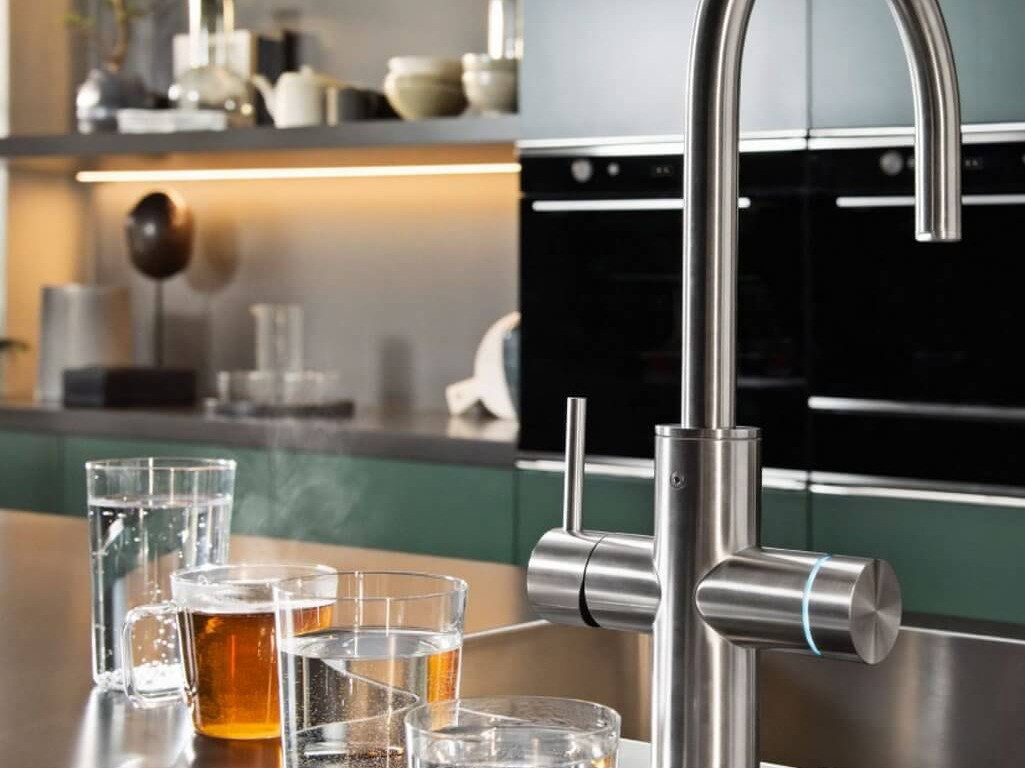 Franke Mythos Armatur aus Edelstahl auf einer modernen Küchenarbeitsplatte mit Gläsern für Wasser und Getränke